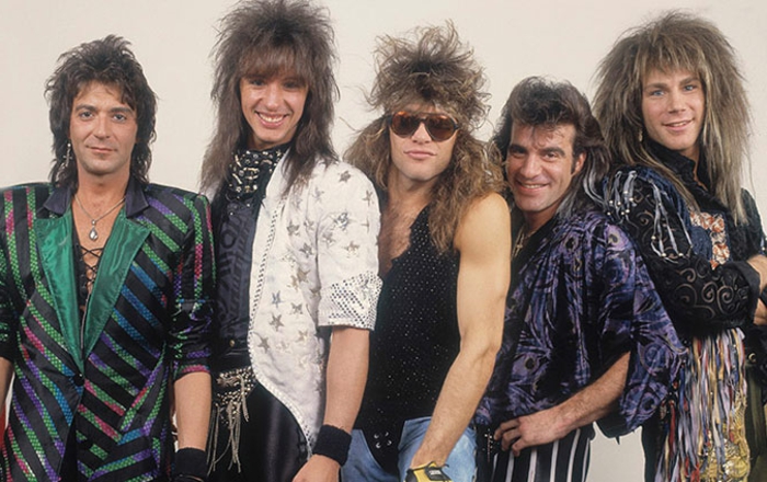 80's fashion for men, bon jovi glam rock band, five men with punk hairstyles and 80s clothing, shiny over-sized blazers with stripes and stars, tassels animal prints jewelry and sunglasses