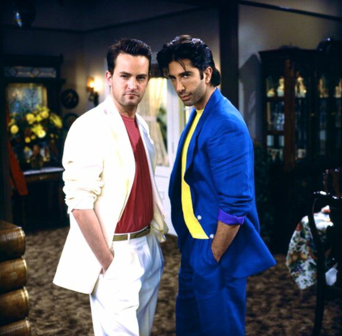 throwback outfits, Matthew Perry and David Schwimmer as Chandler and Ross from Friends, wearing white suit with red t-shirt and blue suit with yellow t-shirt, hands in pockets