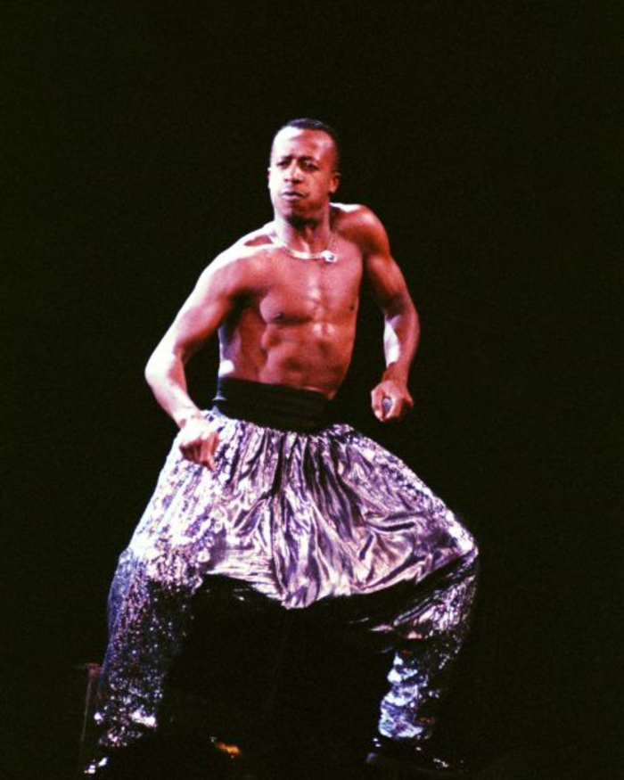80's hip hop fashion, topless African-American man dancing, wearing shiny baggy parachute pants with wide black belt