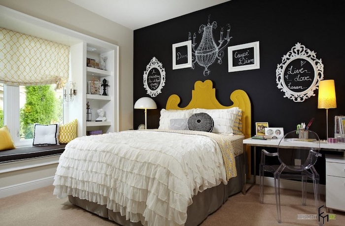 chandelier drawing white, on black wall, decorated with four empty frames, containing messages written in white chalk, large wall art, bed with frilly covers ,and bright yellow headboard