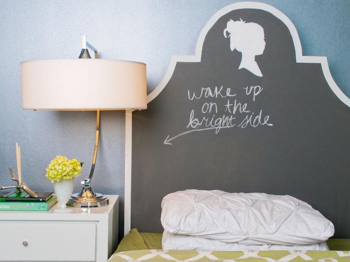 message written in chalk, on black headboard, with silhouette drawing of a female head, near small bed with light green covers, cool decor ideas