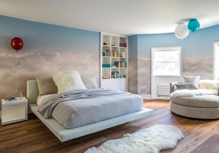 three balloons inside a bedroom, with walls covered in wallpaper or mural, depicting light blue sky, with fluffy cream clouds, wall art décor, white and cream furniture
