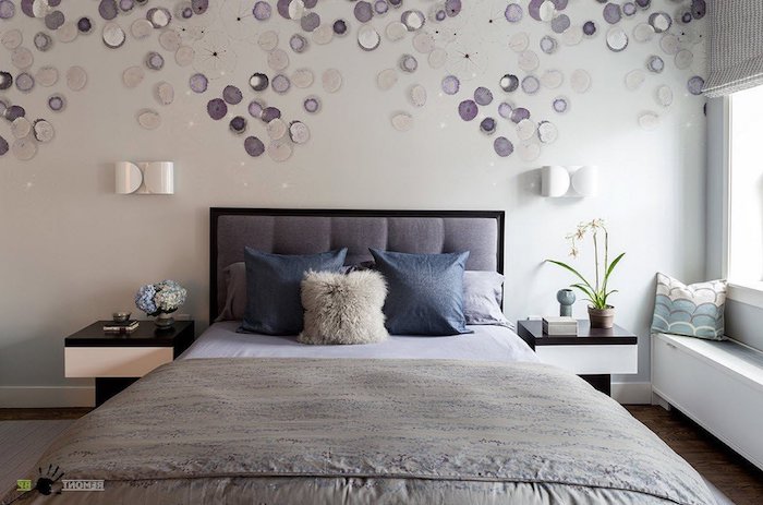 many round off-white and purple decorations, on a wall behind a double bed, bedroom decorating ideas, cushions and covers in different shades of gray 
