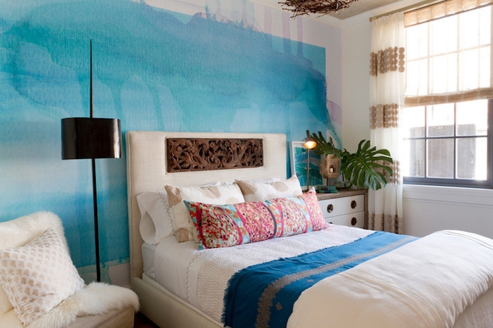 azure blue wall, with watercolor-like effect, and pale smudges of pink paint, bedroom wall decor, inside a room with white bed, with decorative headboard and colorful bedding