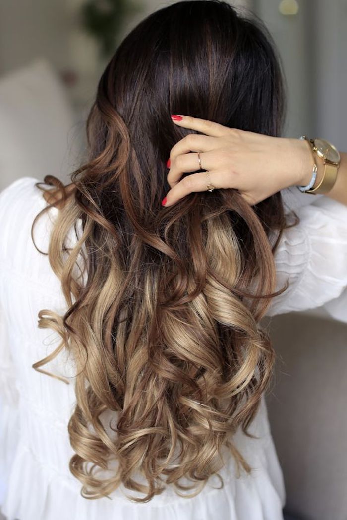 red nail polish, on hand holding a strand of long hair, ombre effect with dark brown top, and caramel highlights at the bottom