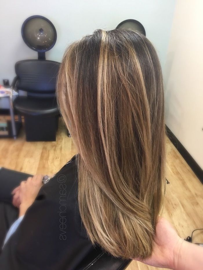 hairdresser holding the tips of a woman's hair, brown and blonde hair, smooth and straightened, brunette with blonde highlights