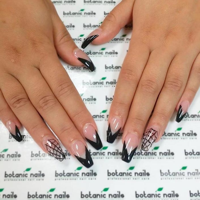 spider webs and geometric shapes in black, on two hands, with clear ballerina nail shape, resting on a white patterned surface