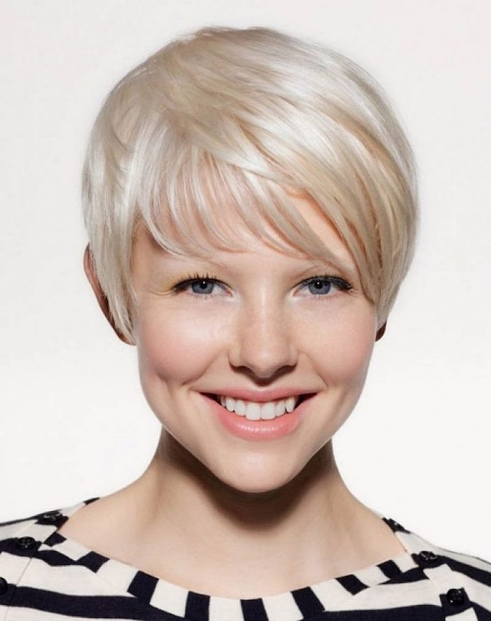 dimpled smiling woman, with platinum blonde messy bob, and side bangs, wearing a striped black and white top