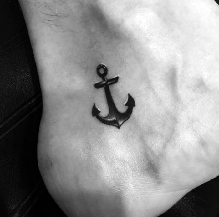 another version of an anchor tattoo, in black with white details, small symbolic tattoos, steadfastness and family, on a man's foot, close to his ankle and sole