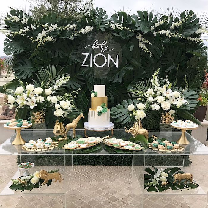 lots of greenery and white flowers, cake and sweets on a glass table, baby shower decoration ideas for boy