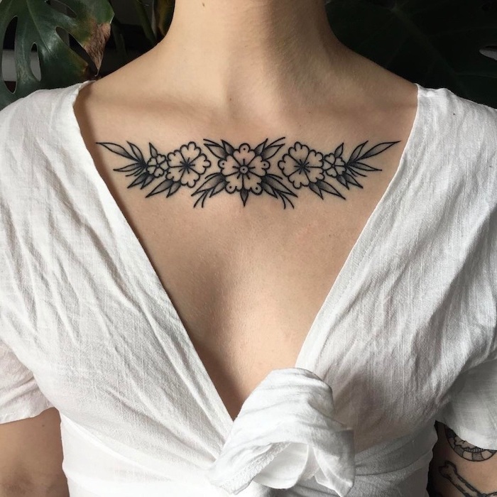 chest tattoo ideas, white shirt, flowers and leaves tattoo, palm leaves in the background