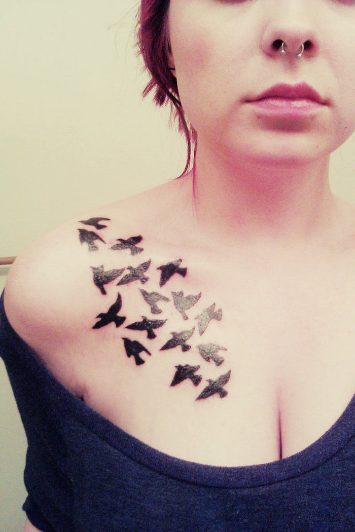 grey top, white background, birds flying on shoulder, tribal chest tattoos, nose earring
