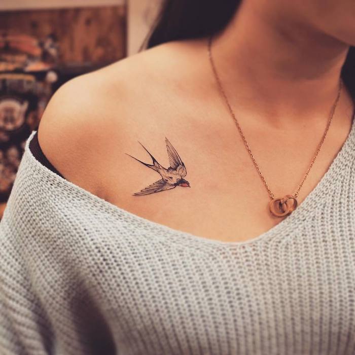 small bird shoulder tattoo, grey sweater, chest tattoos for women, gold necklace