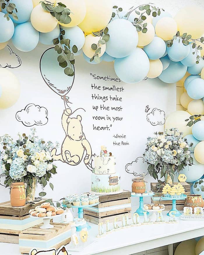 yellow and blue balloon arch, flower bouquets in vases, baby boy baby shower themes. winnie the pooh