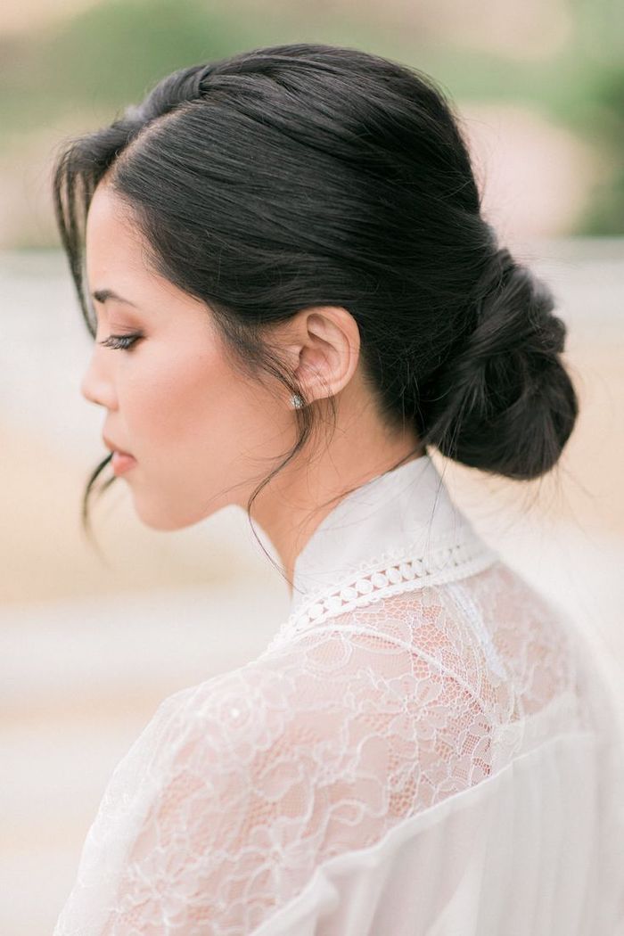 black hair, in a low updo, wedding hairstyles for long hair, white dress with lace