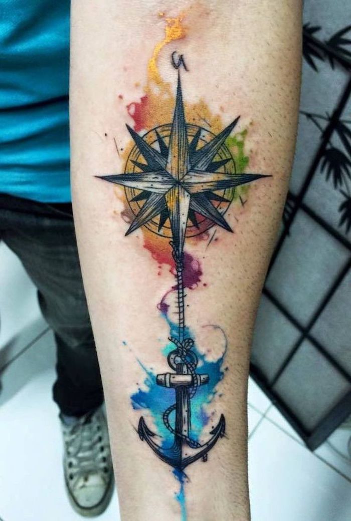 compass and anchor, watercolour forearm tattoo, tattoo ideas for men, man wearing blue shirt and jeans