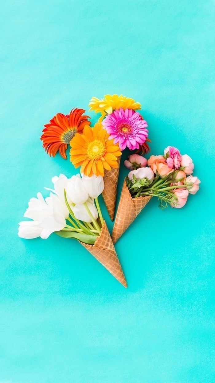 three different flower bouquets, in three ice cream cones, blue phone background, spring photos