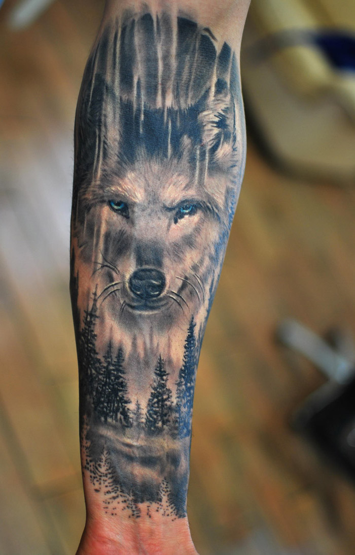 large wolf head, over a forest landscape, forearm tattoo, cool small tattoos, blurred background