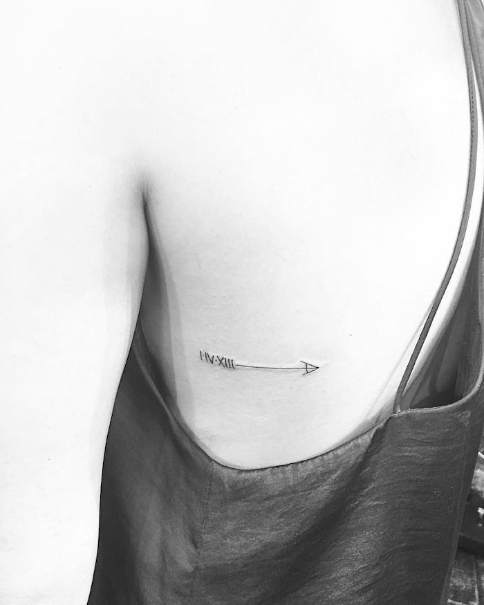 arrow rib cage tattoo, black and white photo, birthday tattoos in roman numerals, black top