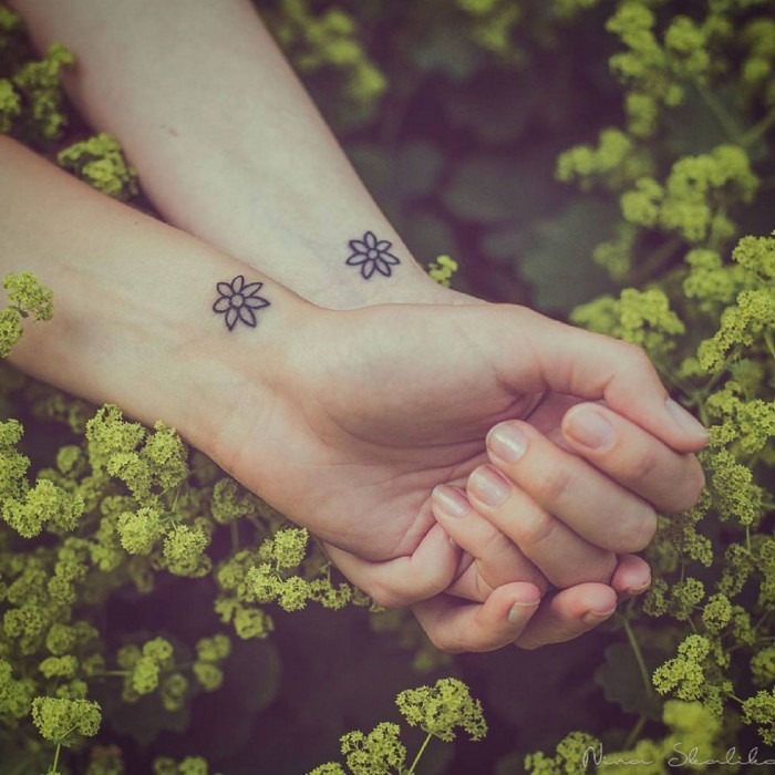 two flowers, wrist tattoos, small bestfriend tattoos, intertwined hands, green bush
