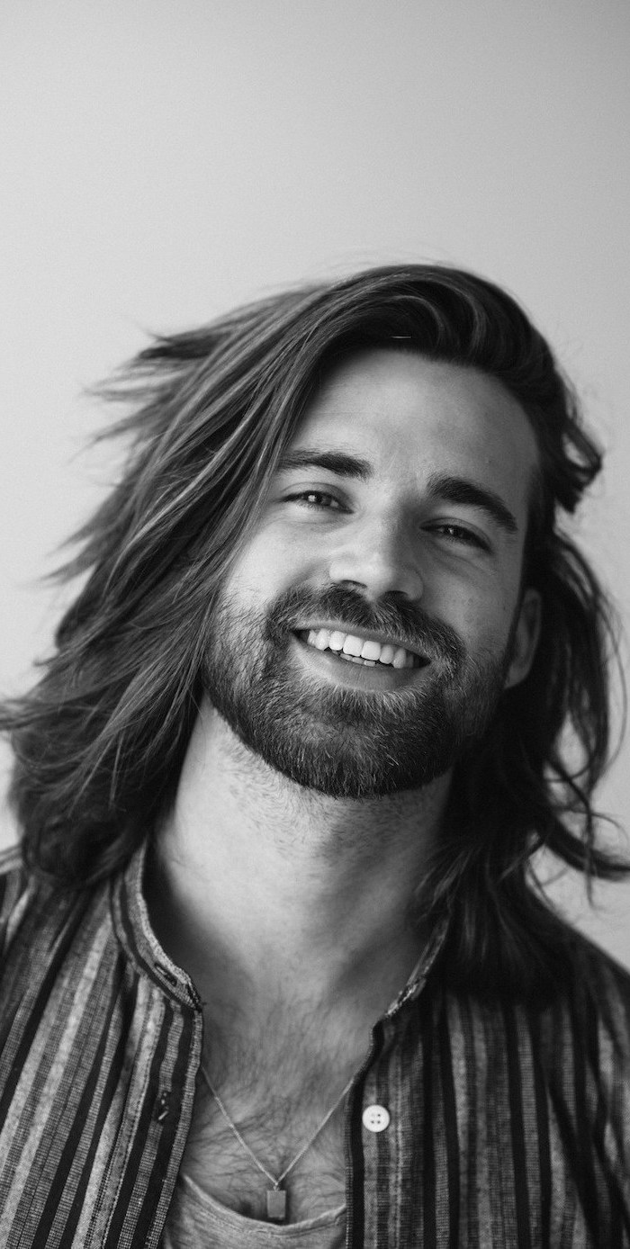 long hairstyles for men, black and white photo, man smiling at the camera