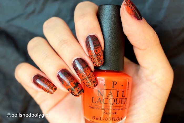 orange nail polish, cute halloween nails, black halloween decorations, holding an orange nail polish bottle