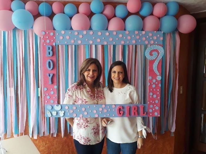 two women smiling, gender reveal pinata, photo frame, in pink and white, lots of balloons