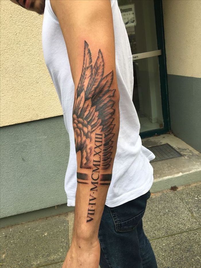 angel wings tattoo on back, roman numerals, arm tattoo, man with white top and jeans