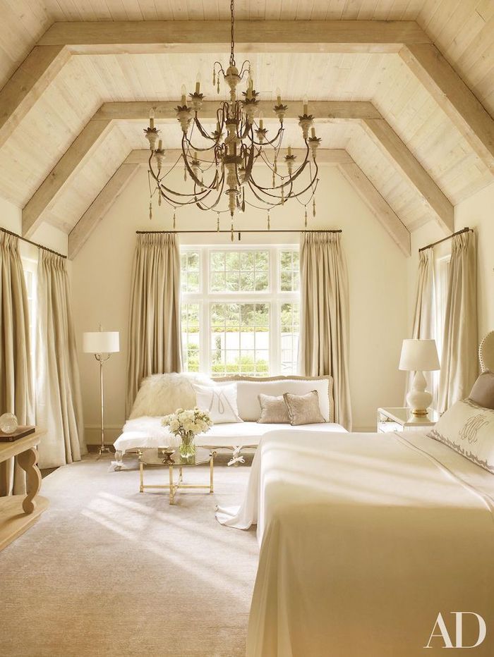 beige bedroom, wooden ceiling, vaulted ceiling, beige curtains, white sofa, hanging chandelier
