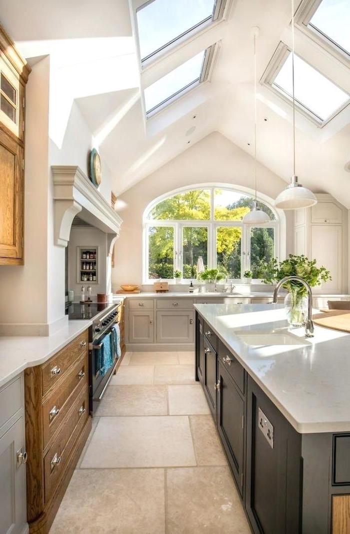white ceiling with skylights, kitchen island, tiled floor, wooden cupboards, hanging lamp shades, what does vaulted mean