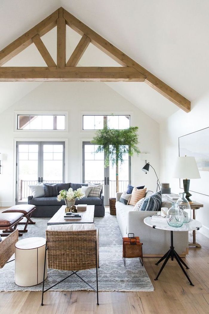 wooden floor, vaulted ceiling beams, white ceiling, white sofa, black leather sofa, blue carpet, tall windows
