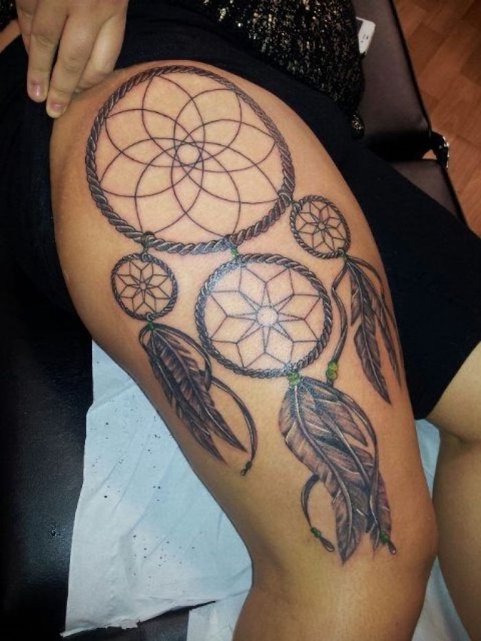 large dreamcatcher, with green beads, thigh tattoos for girls, black shorts, black leather bed
