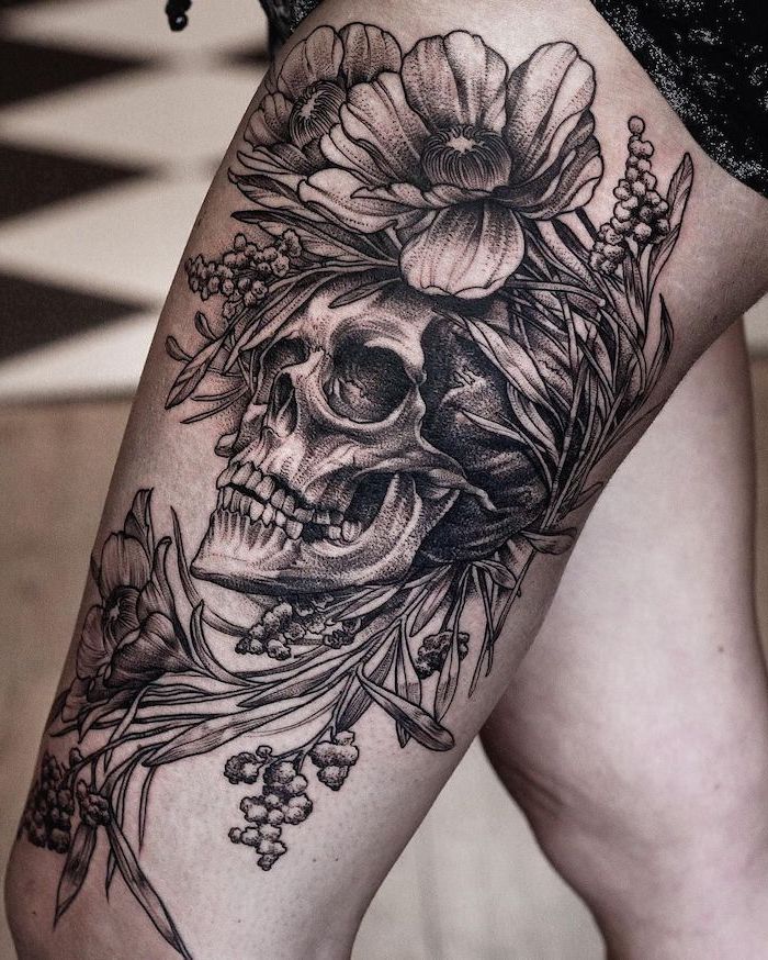 human skull, surrounded by flowers, thigh tattoos for girls, black shorts, tiled floor