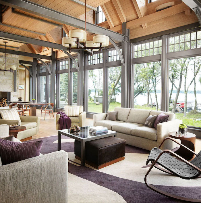metal beams, vault definition, grey sofas, white and purple carpet, tall windows, stone fireplace wall