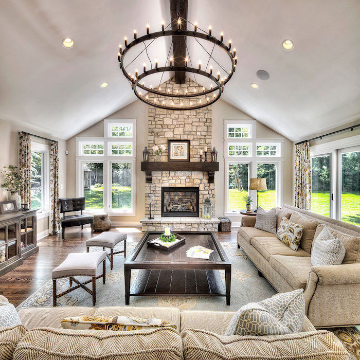 hanging chandelier, beige sofas, throw pillows, vaulted ceiling with beams, wooden table, grey ottomans