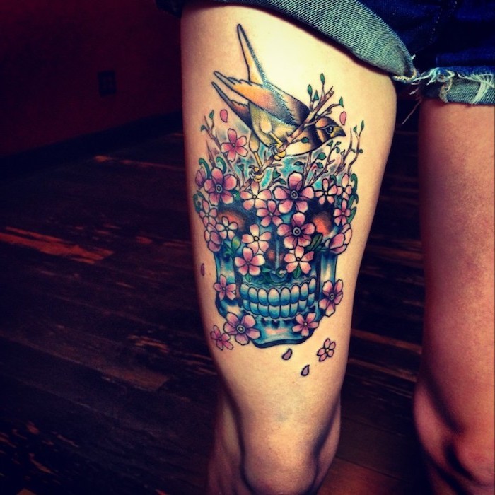 denim shorts, blue skull, pink flowers, hummingbird on top, side thigh tattoo, wooden floor
