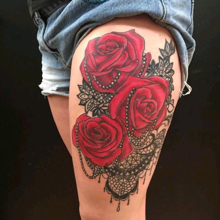three red roses, black beads, mandala flowers tattoo, denim shorts, black background, lion thigh tattoo