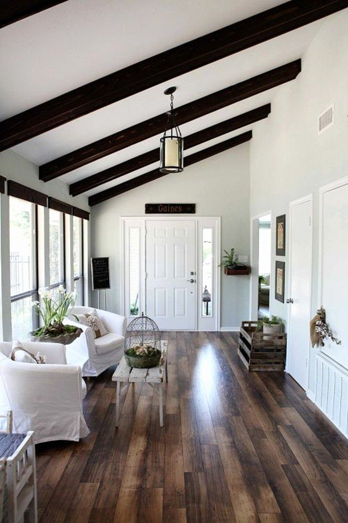 wooden floor, vaulted vs cathedral ceiling, white armchairs, white ceiling, black wooden beams, entry door