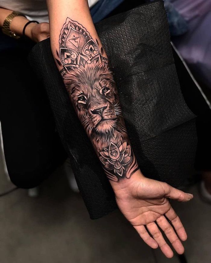 lion head surrounded by mandala lotus flowers, lion chest tattoo, forearm tattoo, black background