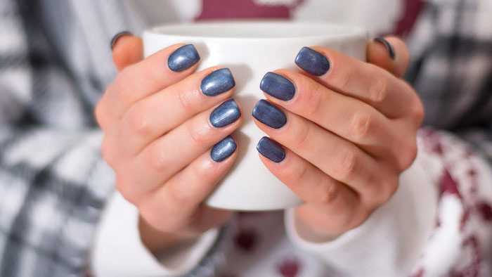 two hands holding a mug, short squoval nails, winter nails, blue glitter nail polish