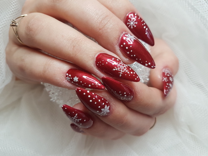 red metallic nail polish, winter nail designs, white snowflakes decorations on each nail, stiletto nails