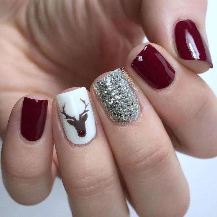 dark red and white nail polish, silver glitter on the middle finger, popular nail colors, reindeer decoration on ring finger