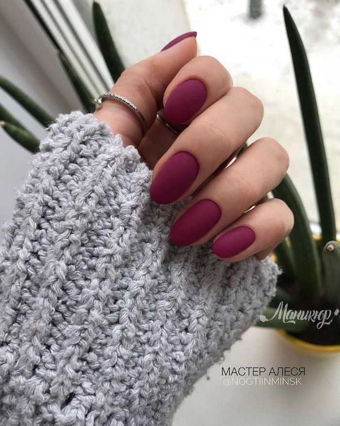 burgundy nail polish, cute nail colors, almond nails, woman wearing grey sweater, rings on thumb and index finger