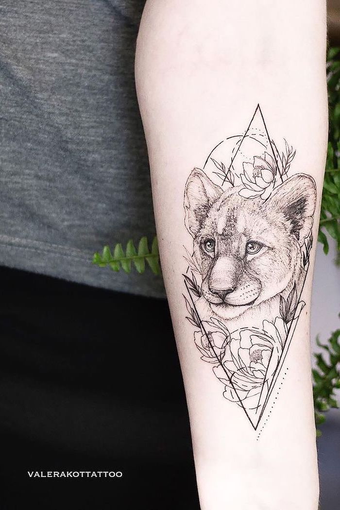 small lion cub tattoo, forearm tattoo, surrounded by flowers, lion tattoos for females, geometrical design