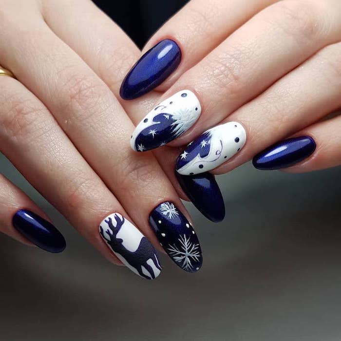 blue and white nail polish, snowflakes and reindeer decorations on middle and ring fingers, winter nail ideas