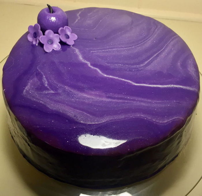 purple and white marble glaze on one tier cake, glaze icing for cake, purple apple and flowers decorations on top